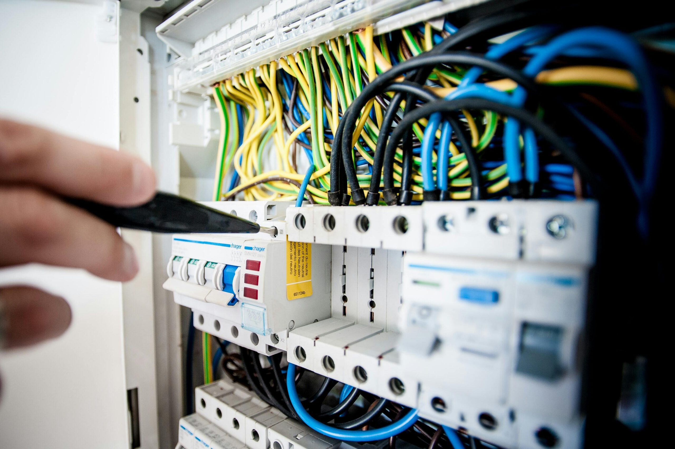Home Hand of electrician working on a circuit breaker panel with colorful wires, ensuring safe electrical connections.