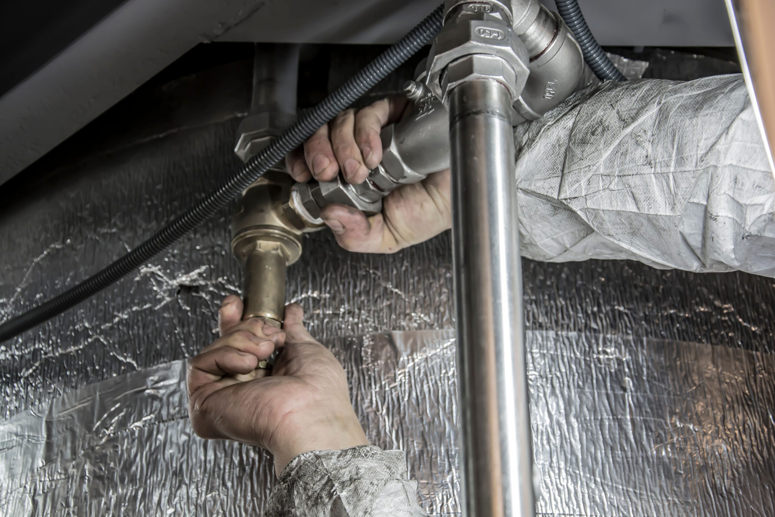 Home Close-up of a plumber's hands installing steel pipes indoors, showcasing skilled manual work.